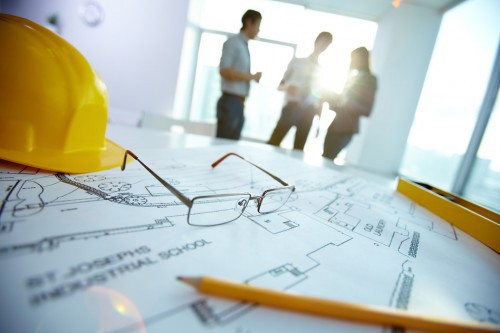 Image of engineering objects on workplace with three partners interacting on background